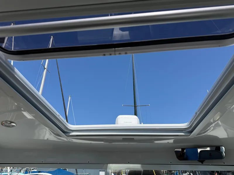 Slide: The Image of Open sunroof view from 2021 Beneteau Antares 8, showcasing clear blue sky and masts. - 16
