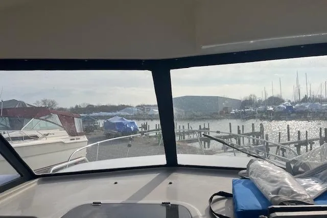 Slide: The Image of 2004 Bayliner 242 Classic boat interior view, overlooking marina with docked boats. - 11