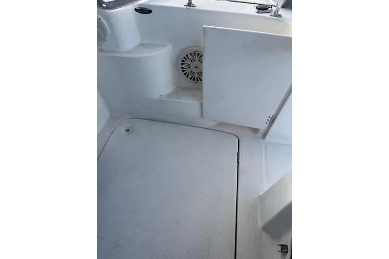 Slide: The Image of 2004 Bayliner 242 Classic boat interior with white deck and storage compartment. - 14