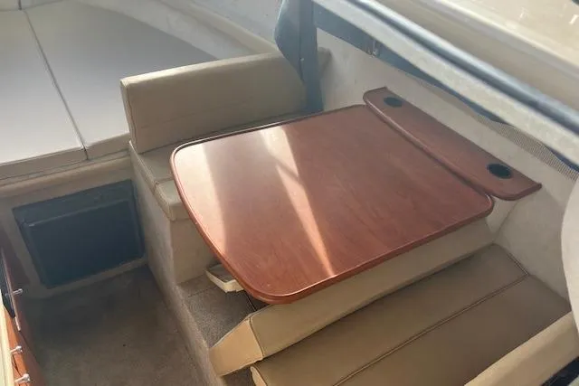 Slide: The Image of 2004 Bayliner 242 Classic interior with wooden table and beige seating. - 20
