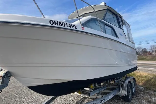 Slide: The Image of 2004 Bayliner 242 Classic boat on trailer, side view, clear sky background. - 4