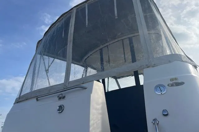Slide: The Image of 2004 Bayliner 242 Classic boat with enclosed cockpit under a clear blue sky. - 5