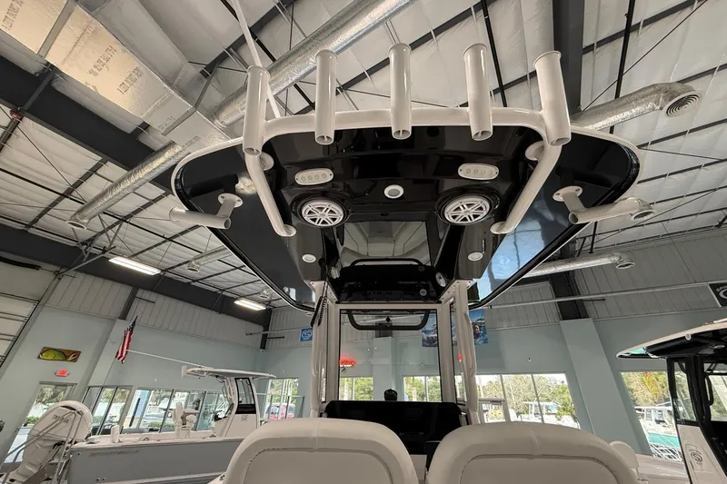 Slide: The Image of 2026 Sportsman Open 232 Center Console boat interior with rod holders and speakers in a showroom. - 2