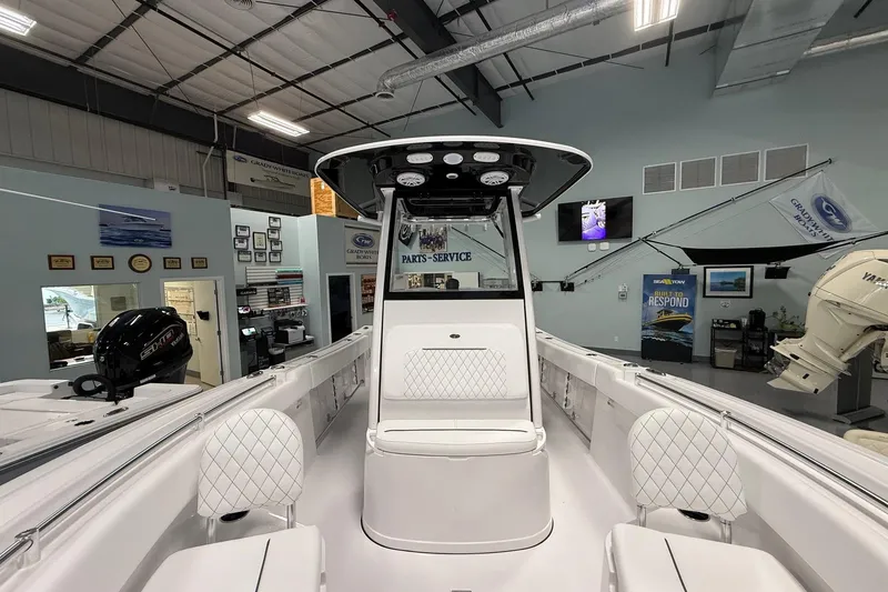 Slide: The Image of 2026 Sportsman Open 232 Center Console boat interior in showroom, featuring white seating and modern design. - 4
