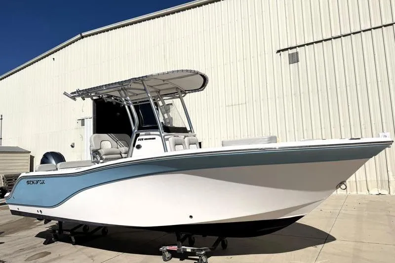 Slide: The Image of 2023 Sea Fox 228 Commander boat with T-top, parked outside a warehouse. - 1
