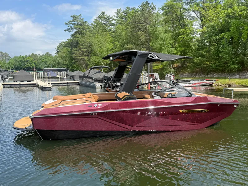 Slide: The Image of A luxurious maroon motorboat is on the water, surrounded by trees and a dock. - 1