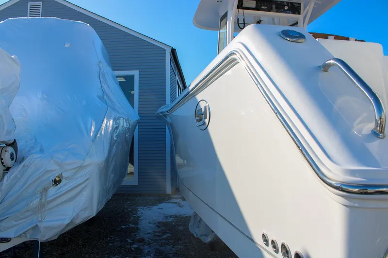 Slide: The Image of 2026 Sea Hunt Gamefish 25 boat beside a covered vessel, near a building. - 51