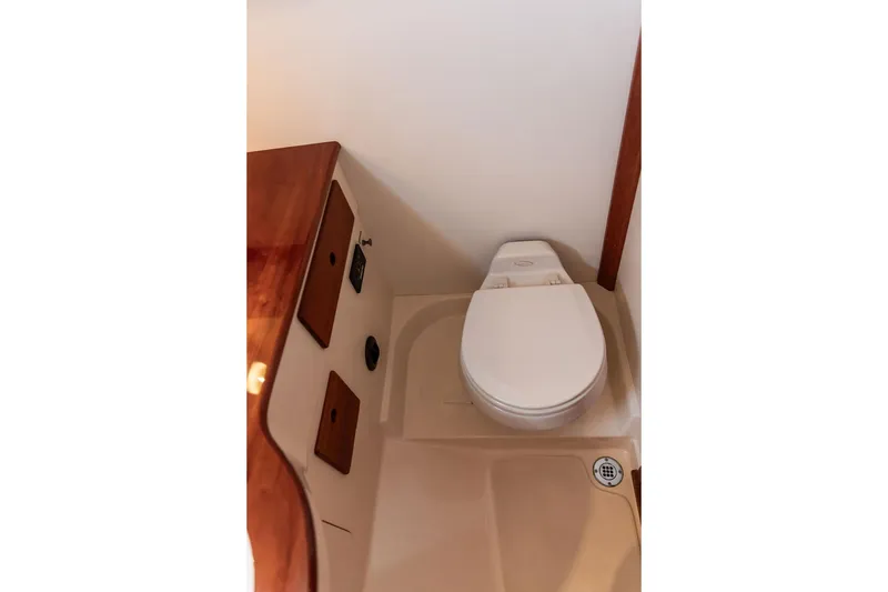 Slide: The Image of 2005 Hinckley Picnic Boat EP bathroom with compact toilet and wooden accents. - 12