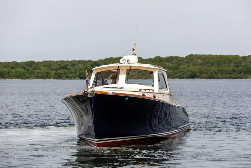 Slide: The Image of 2005 Hinckley Picnic Boat EP cruising on calm waters with lush green shoreline. - 2