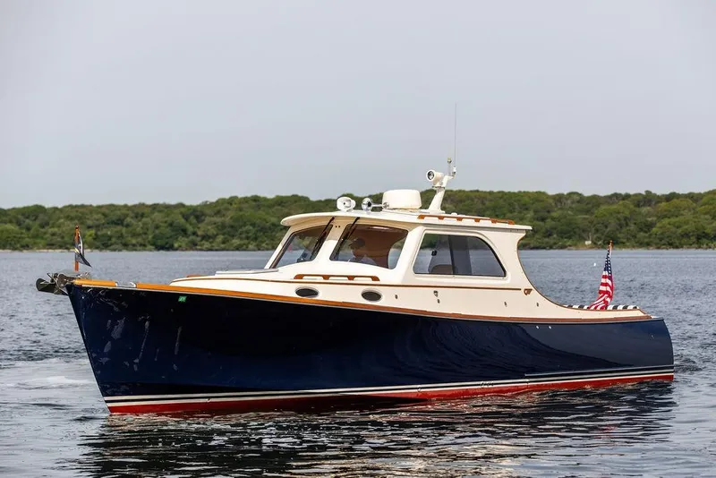 Slide: The Image of 2005 Hinckley Picnic Boat EP cruising on calm waters with lush greenery in the background. - 3