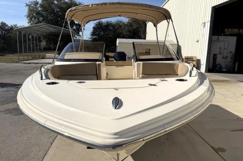 Slide: The Image of 2023 Scout 215 Dorado boat with canopy, parked outside a warehouse. - 3