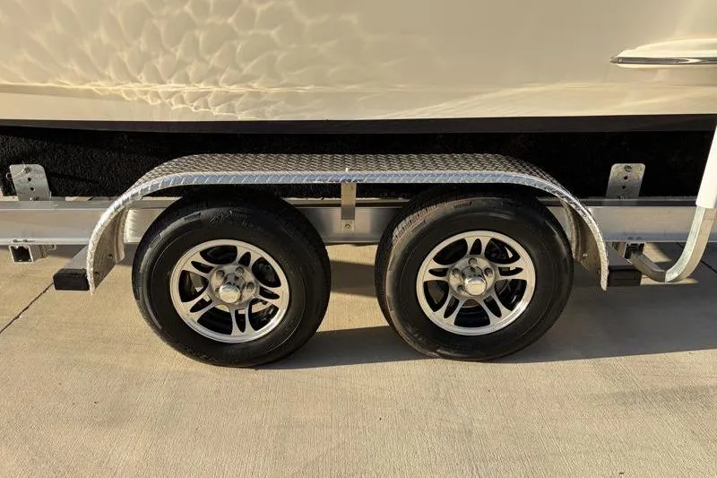 Slide: The Image of Trailer wheels of a 2023 Scout 215 Dorado boat on a concrete surface. - 37