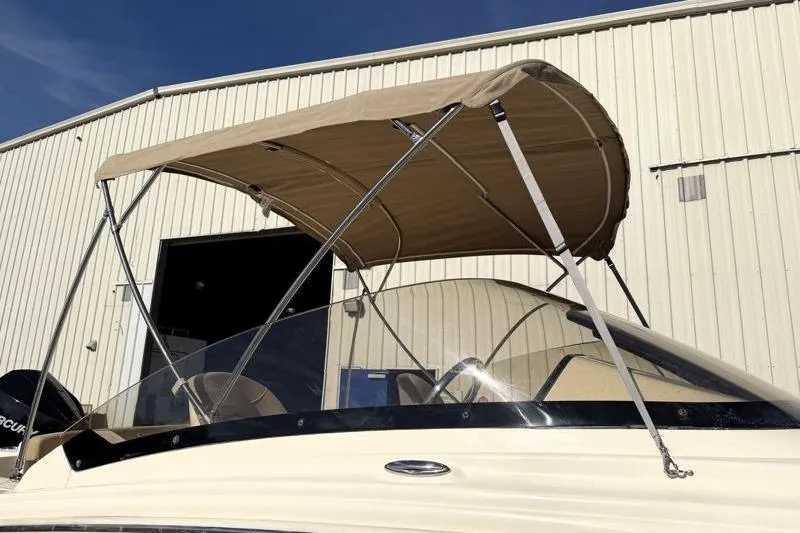 Slide: The Image of 2023 Scout 215 Dorado boat with beige canopy, parked near a warehouse. - 5