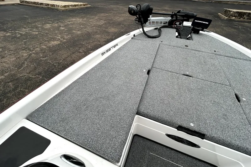 Slide: The Image of 2010 Skeeter 20i boat deck with carpeted surface and fishing equipment. - 11