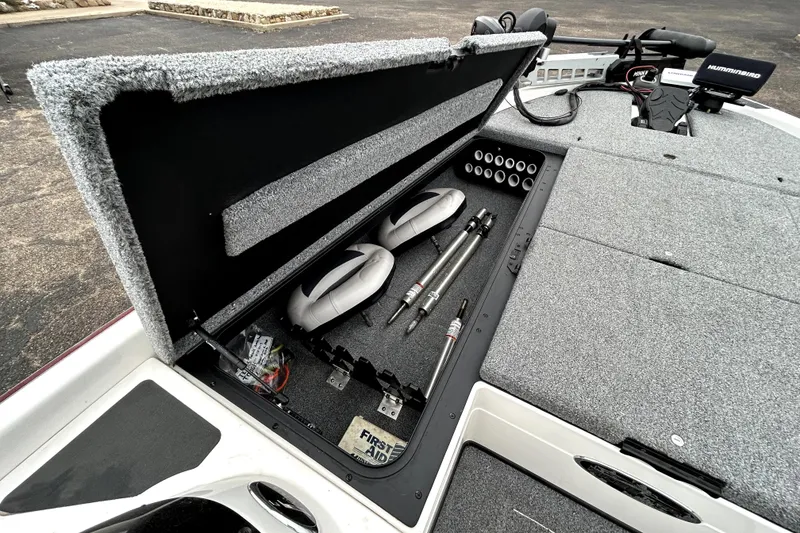 Slide: The Image of Open storage compartment in a 2010 Skeeter 20i boat, showing equipment and first aid kit. - 12
