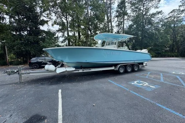 The Image of 2014 Jupiter 34 boat on trailer in parking lot, surrounded by trees. - 0