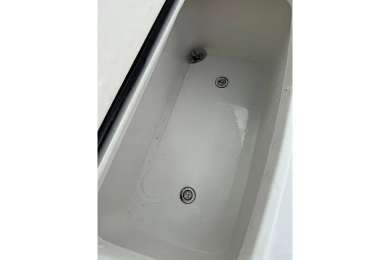 Slide: The Image of Livewell compartment in a 2014 Jupiter 34 boat, featuring drainage outlets. - 13