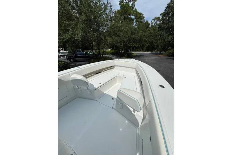 Slide: The Image of 2014 Jupiter 34 boat interior with seating, surrounded by trees and parked vehicles. - 7