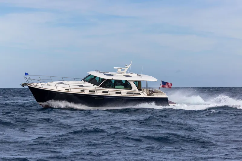 Slide: The Image of 2027 Sabre 51 Salon Express yacht cruising on open sea with American flag. - 7