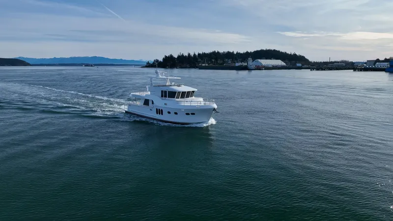 Slide: The Image of 2024 Northwest 55 yacht cruising on calm waters near a scenic coastline. - 10