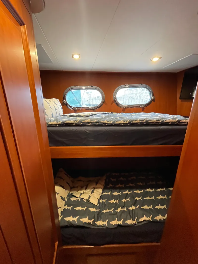 Slide: The Image of Bunk beds in 2024 Northwest 55 yacht cabin with porthole windows and shark-themed bedding. - 32