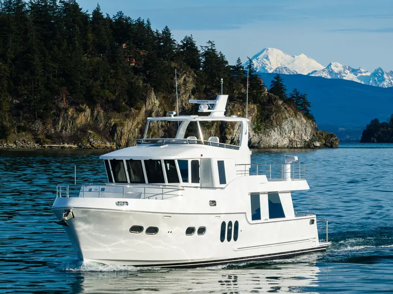 Slide: The Image of 2024 Northwest 55 yacht cruising near forested coastline and snowy mountains. - 5