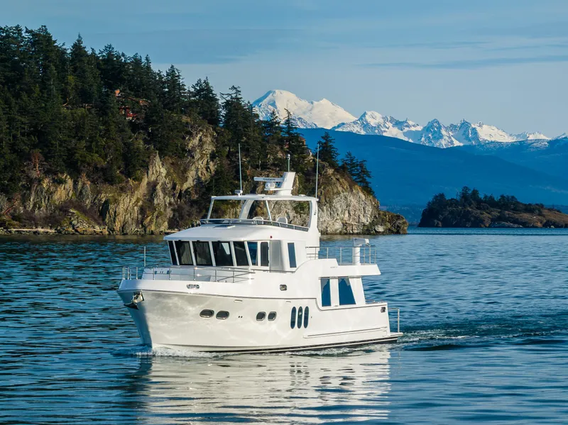 Slide: The Image of 2024 Northwest 55 yacht cruising near forested coastline and snowy mountains. - 9