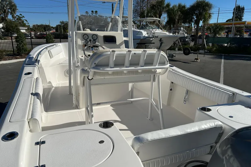 Slide: The Image of 2011 Tidewater 216 CC Adventure boat interior with seating and console, parked outdoors. - 12