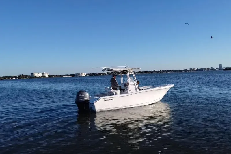 Slide: The Image of 2011 Tidewater 216 CC Adventure boat on calm water under clear blue sky. - 20