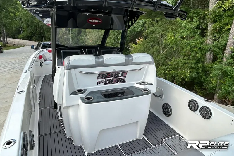 Slide: The Image of 2013 Sunsation 34 CCX boat interior with seating and cup holders, surrounded by lush greenery. - 17