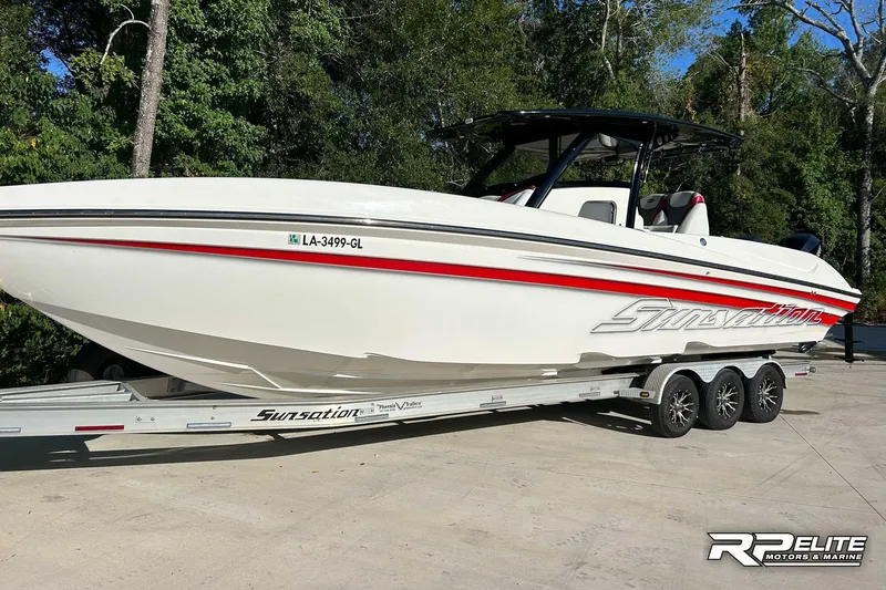 Slide: The Image of 2013 Sunsation 34 CCX boat on trailer, white with red accents, parked outdoors. - 26
