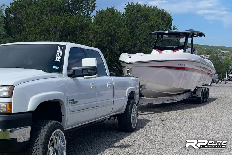 Slide: The Image of White truck towing 2013 Sunsation 34 CCX boat on a trailer in a parking area. - 31