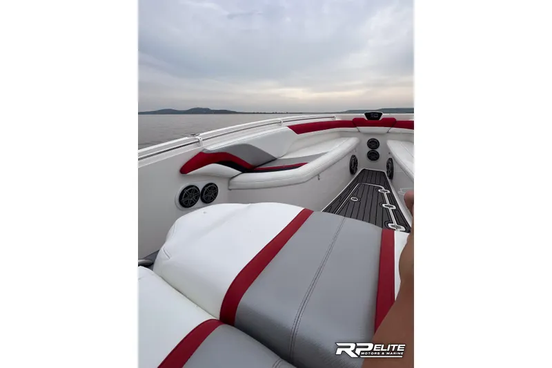 Slide: The Image of 2013 Sunsation 34 CCX boat interior with red and gray seating, on a calm lake. - 33