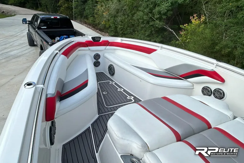 Slide: The Image of 2013 Sunsation 34 CCX boat interior with red and gray seating, parked near a black truck. - 8