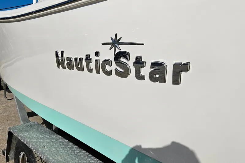 Slide: The Image of 2018 NauticStar 25 XS boat logo on hull, displayed on a trailer. - 19