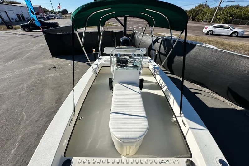 Slide: The Image of 2014 Young Boats 20 Bay Boat with green canopy and white seating, parked outdoors. - 38