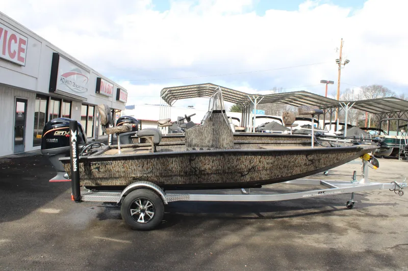 The Image of 2026 Xpress H190B Bay boat on trailer at dealership, featuring camouflage design. - 1
