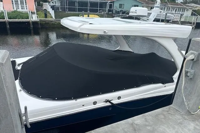 Slide: The Image of 2019 Regal 33 OBX boat docked, covered with a black tarp, near waterfront homes. - 39