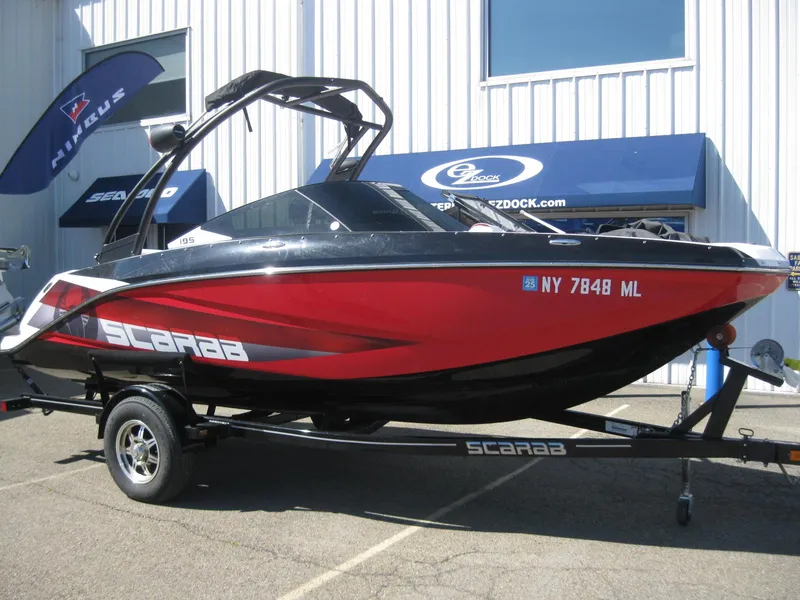 Slide: The Image of 2016 Scarab 195 HO Impulse boat in red and black on a trailer. - 1