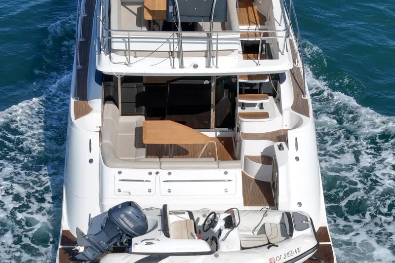 Slide: The Image of 2018 Sea Ray Fly 510 yacht cruising on ocean, showcasing spacious deck and seating area. - 7