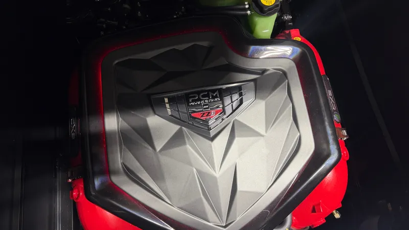 Slide: The Image of Engine cover with PCM logo and red accents, part of a Nautique Super Air Nautique G25. - 38