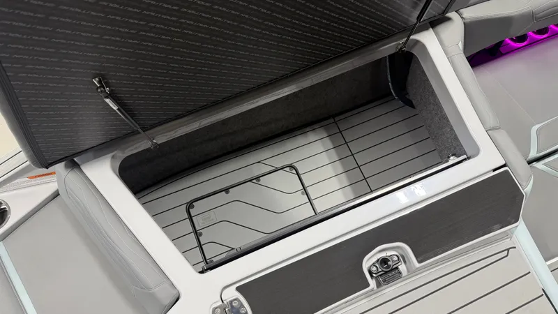 Slide: The Image of Storage compartment in the rear of a 2026 Nautique Super Air Nautique G25 with gray upholstery and purple lighting. - 18