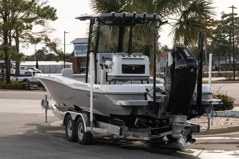 Slide: The Image of 2026 Caymas 28 HB boat on trailer, parked outdoors near palm trees. - 5