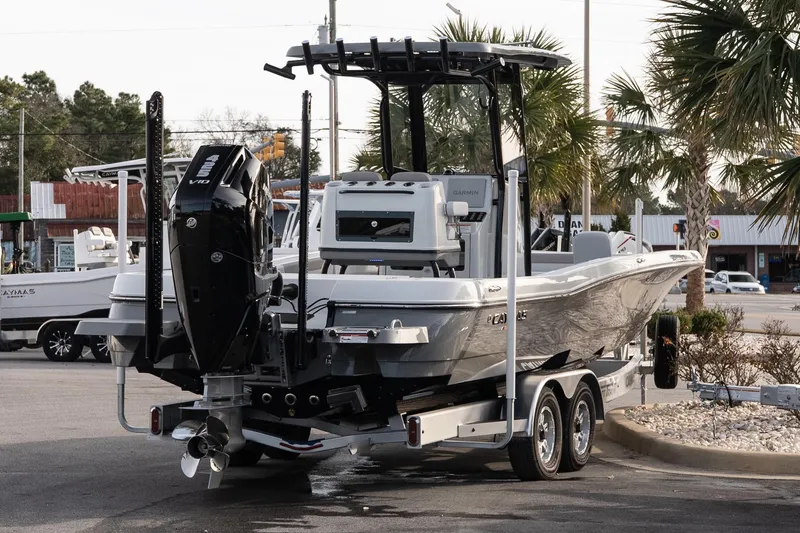 Slide: The Image of 2026 Caymas 28 HB boat on trailer, featuring powerful outboard motor, parked outdoors. - 7
