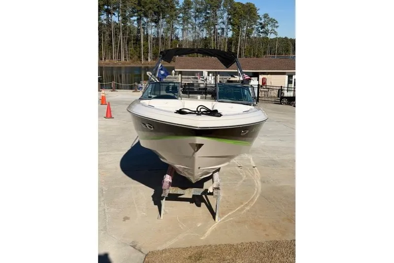 Slide: The Image of 2005 Regal 2200 Bowrider boat on trailer, parked near a lake with trees in background. - 4