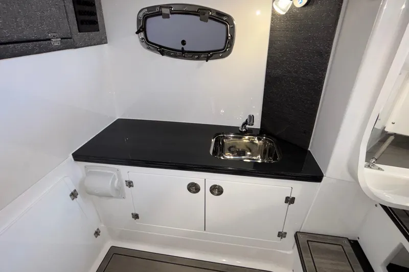 Slide: The Image of Interior of 2026 Monterey Elite 30 OB boat featuring a compact sink and storage cabinets. - 79