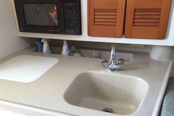 Slide: The Image of 2001 Pursuit 3000 Express boat kitchen with sink, microwave, and storage cabinets. - 10