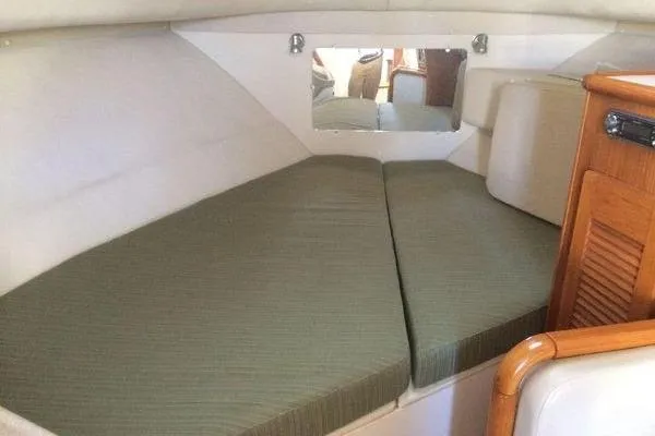 Slide: The Image of 2001 Pursuit 3000 Express cabin interior with green cushions and wooden cabinetry. - 9