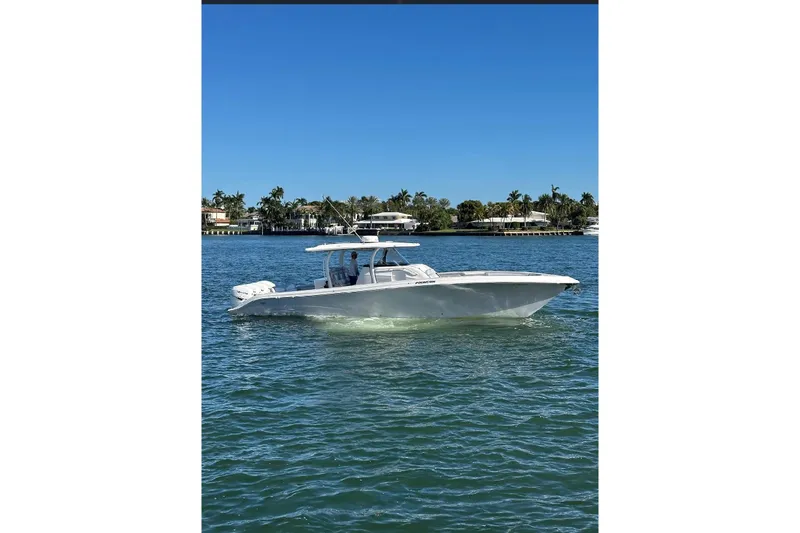 The Image of 2021 Fountain 43 NX boat cruising on clear blue water near luxury waterfront homes. - 0