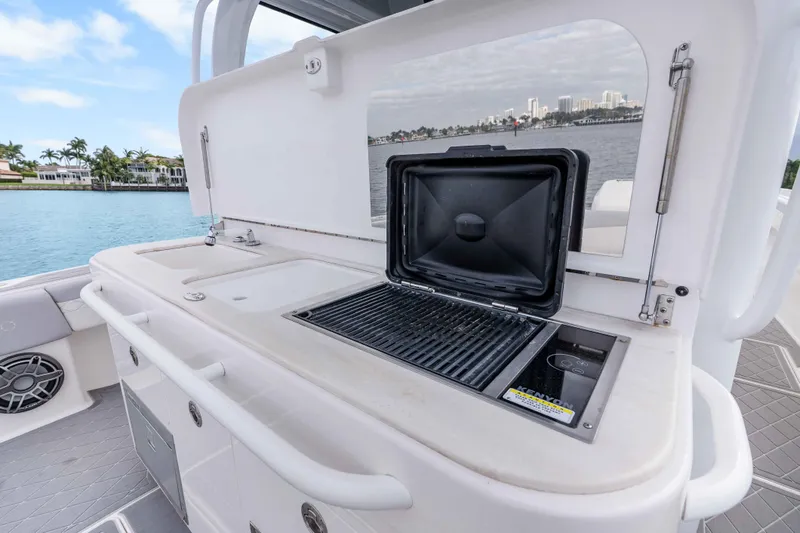 Slide: The Image of Outdoor kitchen on 2021 Fountain 43 NX boat with grill and sink, overlooking waterfront homes. - 40